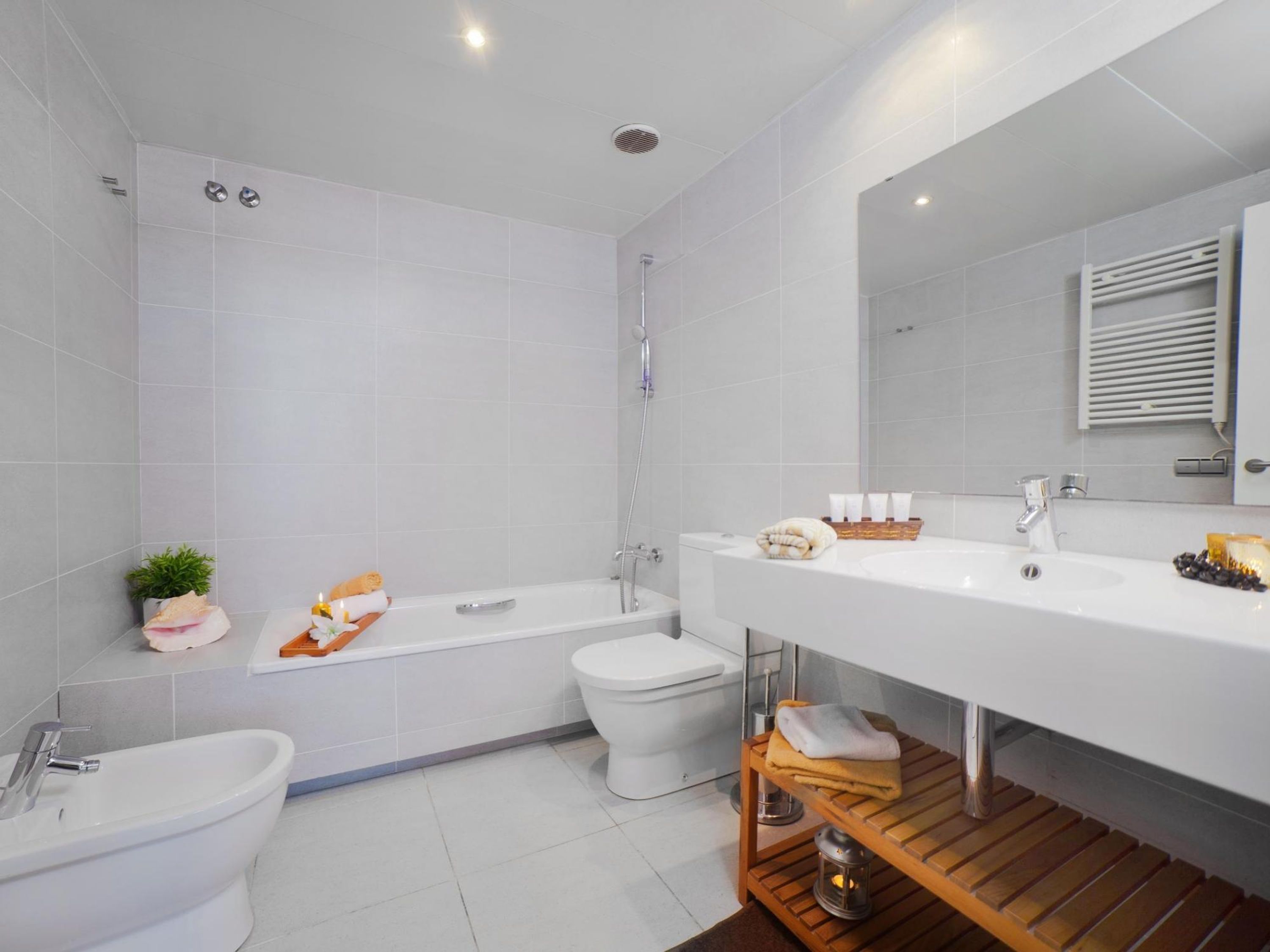Un baño moderno con bañera, inodoro, bidé y tocador con espejo.