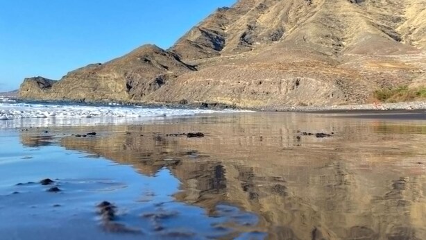 Een berg die helder in het water weerspiegelt.
