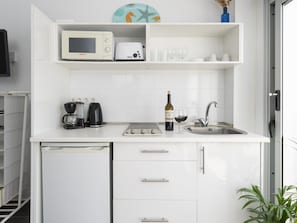 Eine kleine Küche mit Mikrowelle, Toaster, Kaffeemaschine und einer Weinflasche.