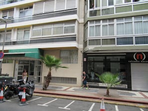 Ein mehrstöckiges Gebäude, ein Laden mit Schaufenster und abgestellte Roller.