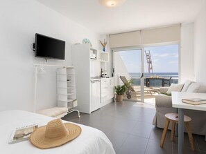 A modern, well-lit room with a bed, a white sofa, a dining table, and a balcony with a view of the sea. - Apartamento Mars n Las Canteras Vista mar 308 (Las Palmas de Gran Canaria)