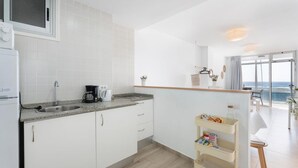 A modern kitchen with white cabinets, a built-in microwave, a coffee maker, and a small cart with snacks.