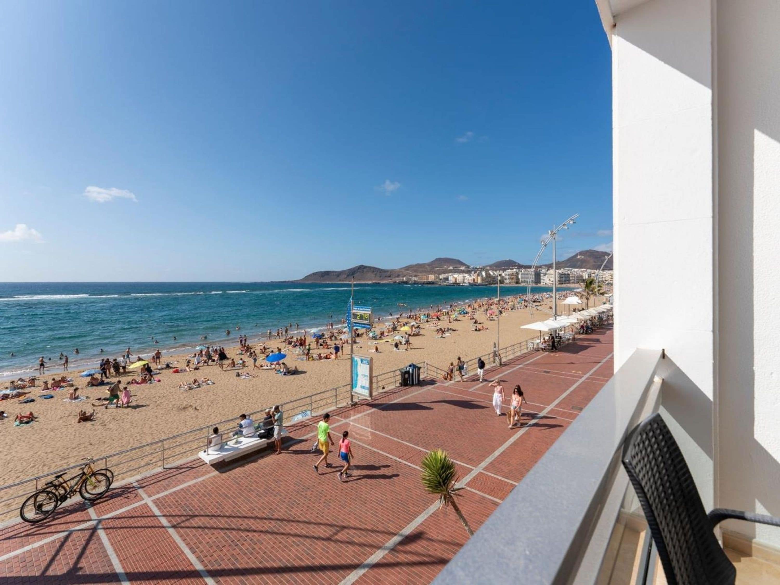 A beach with people, umbrellas, and a clear sky.