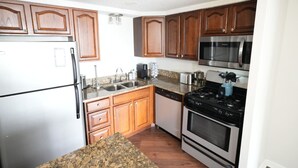 A kitchen with wooden cabinets, stainless steel appliances, granite countertops, and a black stove. - Travel Professionals Downtown (Nashville)