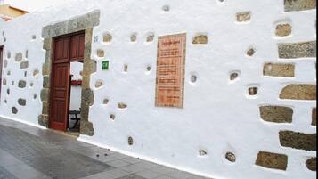 A white building with a stone facade, a wooden door, and a sign on the wall.