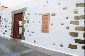 Un edificio blanco con fachada de piedra, una puerta de madera y un letrero en la pared.