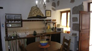 Une cuisine équipée d’une table à manger, de chaises, d’un lustre et d’un four à micro-ondes.