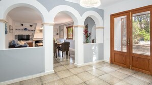 A spacious interior with a dining area, kitchen, and a large wooden door leading outside. - Sa Volta Nova Beautiful House in Countryside (Porreres)