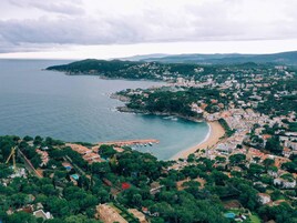 Vista aérea de un pueblo costero con playa, abundante vegetación y edificios.