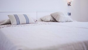 A neatly made bed with a floral-patterned bedspread and two pillows, one with a striped design. - Apartament Reformat a 2 Minuts de la Platja (Palafrugell)