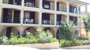 A multi-story building with balconies, outdoor seating, and a sign indicating the property is for sale. - Apartament Reformat a 2 Minuts de la Platja (Palafrugell)
