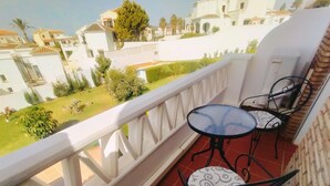A balcony with two chairs and a small table, overlooking a residential area with houses and greenery. - Casa Cipreses 4 Nerja (Nerja)