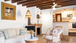 Sala de estar con sofá, sillas de mimbre, chimenea y una zona de cocina con microondas.