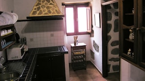 A compact kitchen with a tiled backsplash, a built-in stove, a sink, and a window with a view.