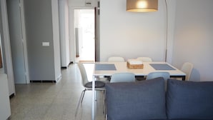 Ein modernes Wohnzimmer mit einer Couch, einem Esstisch mit Stühlen und einer Stehlampe.