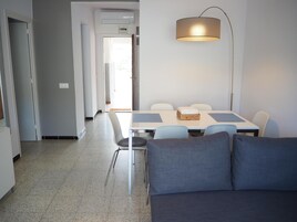 Una sala de estar moderna con un sofá, una mesa de comedor con sillas y una lámpara de pie.