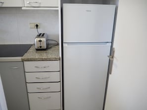 A kitchen with a white refrigerator, a toaster, and a granite countertop.