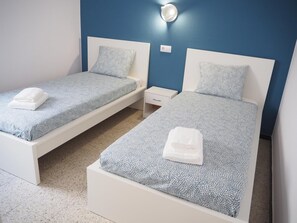 Two twin beds with matching blue patterned bedding and white headboards, each with a white bedside table and a small drawer. - Apartamento Reformado CON Vistas AL MAR (Torroella de Montgrí)