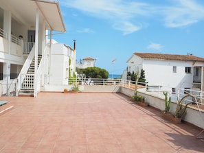 A spacious rooftop terrace with terracotta tiles, white railings, and potted plants. - Apartamento Reformado CON Vistas AL MAR (Torroella de Montgrí)