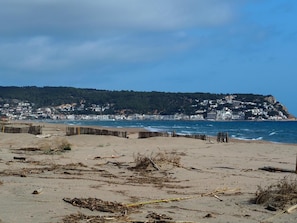 A beach with a wooden fence, sandy shore, and a town in the background. - Apartamento Reformado CON Vistas AL MAR (Torroella de Montgrí)