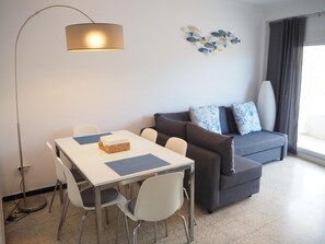Una sala de estar moderna con una mesa de comedor, sillas, un sofá y una lámpara de pie.