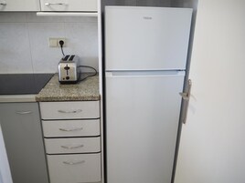 Una cocina con un refrigerador blanco, una tostadora y una encimera de granito.