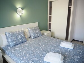 A neatly made bed with a patterned bedspread, a bedside table, and a nightstand. - Apartamento Reformado CON Vistas AL MAR (Torroella de Montgrí)