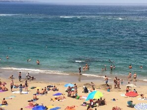 A crowded beach with people swimming and sunbathing, and umbrellas providing shade. - Estudio Interior con Wifi Plata de las Canteras (Las Palmas de Gran Canaria)
