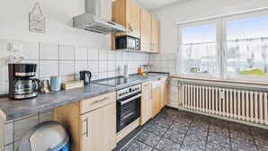 Una cocina moderna con armarios de madera, microondas integrado, estufa y ventana con vista a la ciudad.