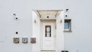 Un edificio blanco con una puerta, un ventanal pequeño y tres cajas fuertes.