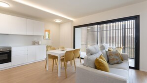 A modern kitchen with white cabinets, a dining area with a table and chairs, and a sofa with cushions. - Apartamento Roca Paraiso DE Agaete CON Vistas (Agaete)