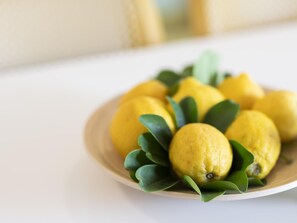 Une assiette de citrons avec des feuilles vertes, posée sur une surface blanche.
