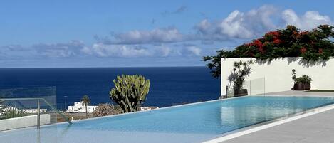 A modern outdoor swimming pool with a clear view of the ocean.