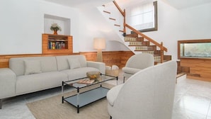 A modern living room with a sofa, armchair, coffee table, and a bookshelf. - CA SA Padrina in Col nia de Sant Jordi (Ses Salines)