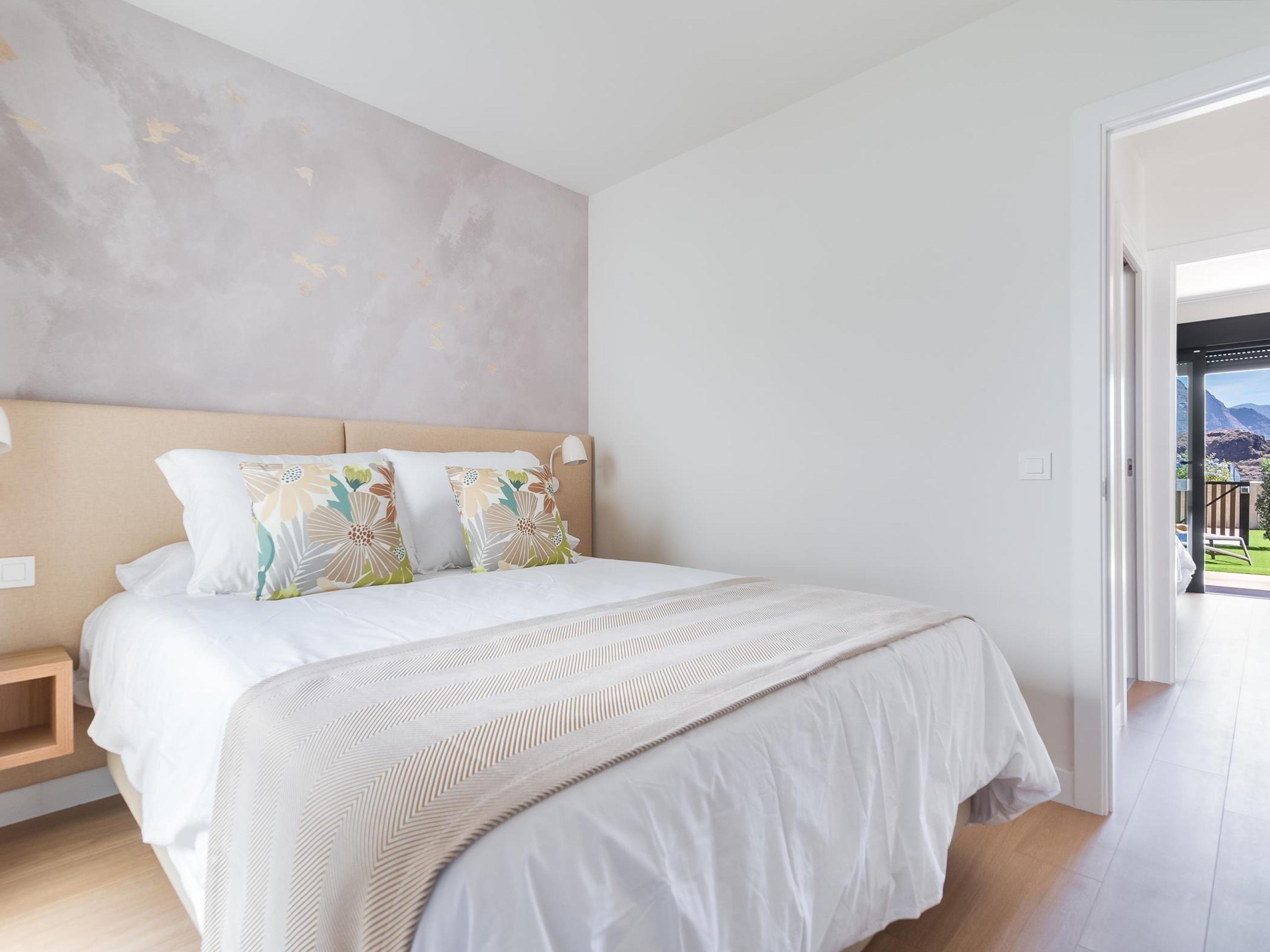 Une chambre à coucher avec un grand lit, une tête de lit et une vue sur l’extérieur.