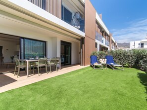 A modern outdoor patio with a dining table and chairs, a grassy lawn, and two sun loungers. - Para so de Agaete Stunning Views and sea Scense (Agaete)