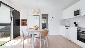 A modern kitchen with white cabinetry, a built-in oven, and a microwave.