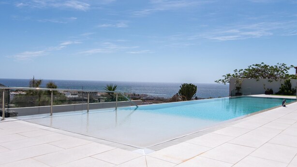 A rooftop infinity pool with a clear view of the ocean.
