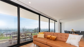 A modern living room with a large window, a sofa, and a dining area.