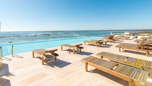 A poolside area with lounge chairs and a view of the sea.