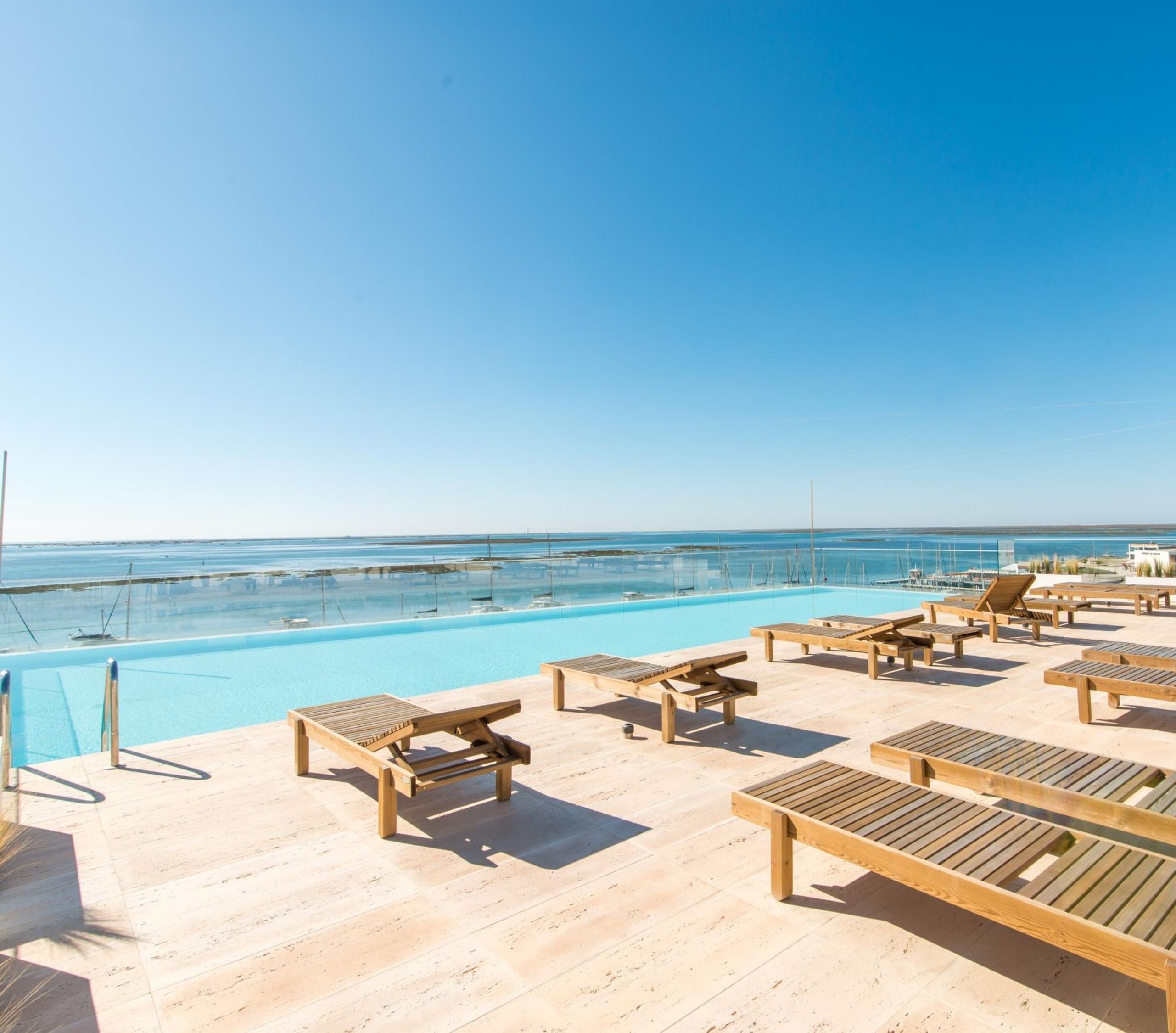 A poolside area with lounge chairs and a view of the sea.