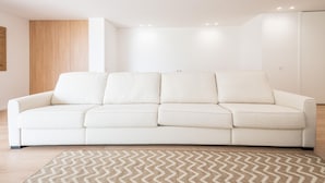 A modern living room with a white sofa, a patterned rug, and recessed ceiling lighting. - Waterfront Luxury On Ria Formosa (Olhao)