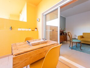 Ein Essbereich mit einem Holztisch und Stühlen, eine Schiebetür zu einem Wohnzimmer mit einer Couch und einem Schrank.