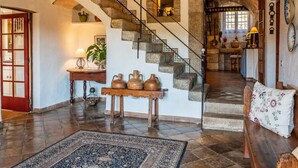 Un intérieur rustique avec un escalier en pierre, un banc en bois et un tapis.