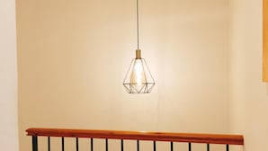 Un escalier doté d’une rampe en bois et d’un luminaire suspendu aux formes géométriques.