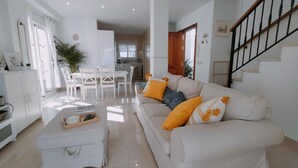 Un salón amplio con sofá, reposapiés y zona de comedor.