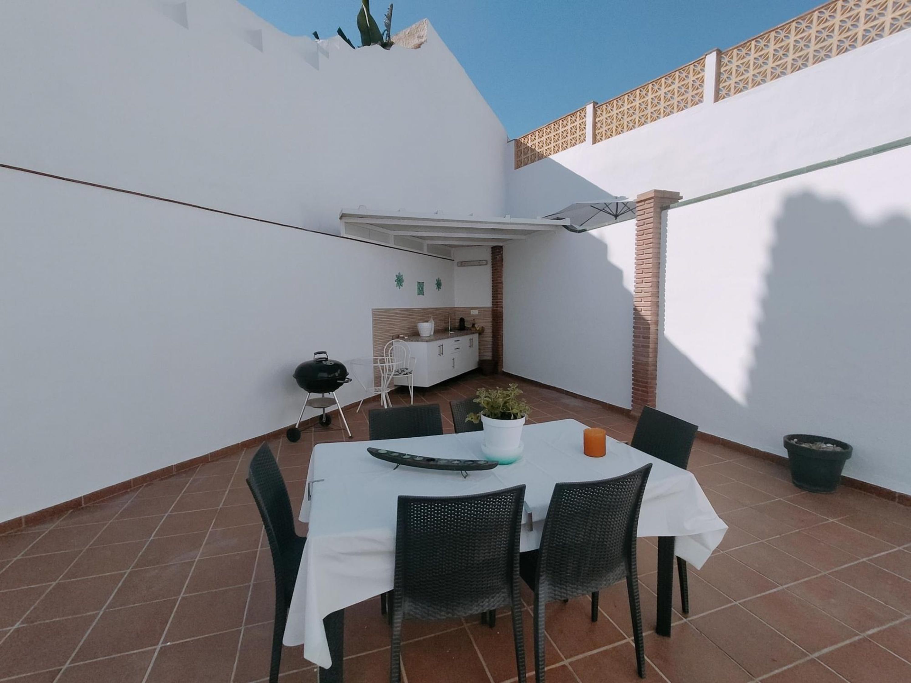 A patio with a table and chairs, a grill, and a small kitchen area.