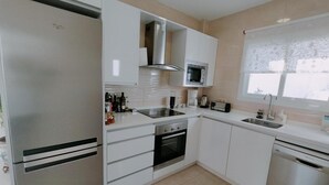 Una cocina moderna con armarios blancos, electrodomésticos de acero inoxidable y un ventanal con vistas.