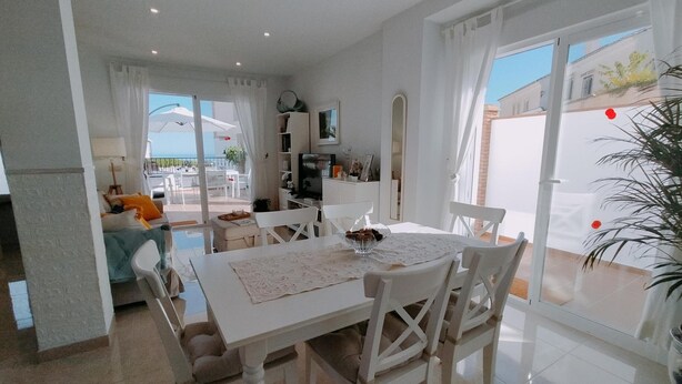 Un comedor amplio con una mesa grande y sillas, una cocina al fondo, y vistas al exterior.
