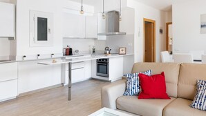 A modern kitchen with white cabinets, a stainless steel range hood, and a built-in oven. - Maka Beach Apartment V (Castelldefels)
